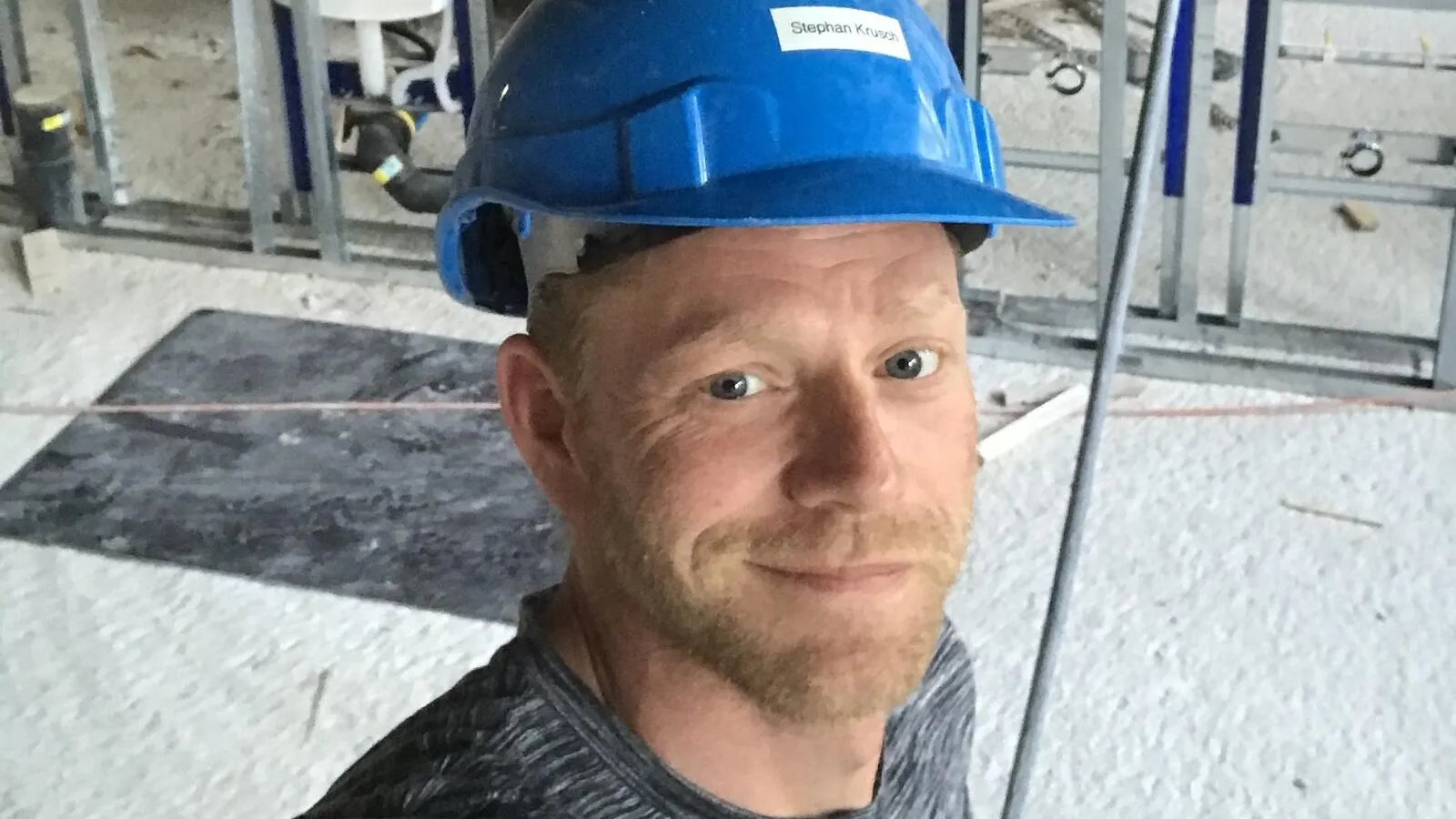 Foto von Handwerker Stephan Krusch mit blauem Schutzhelm.